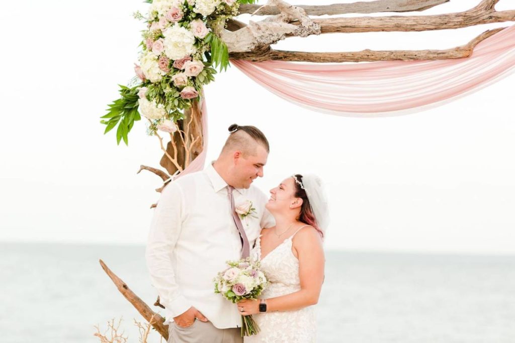 Outer Banks Vow Renewal Couple looking at each other smiling in front of wedding arch