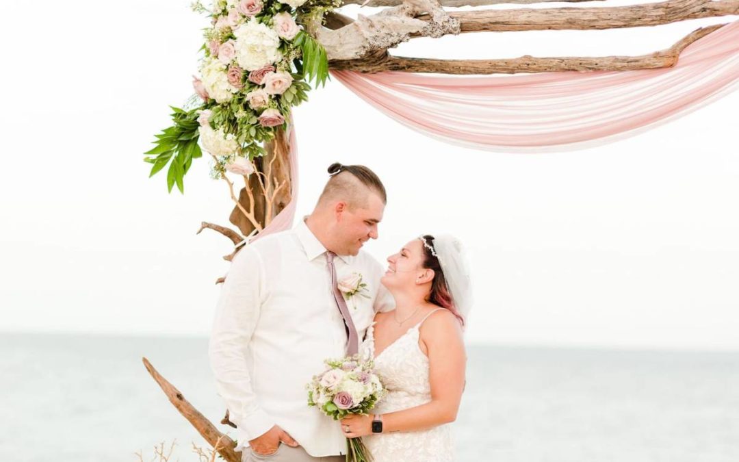 Outer Banks Vow Renewal Couple looking at each other smiling in front of wedding arch